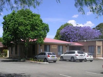 A Karabi neighbourhood centre on a sunny day, with a jacaranda tree in bloom